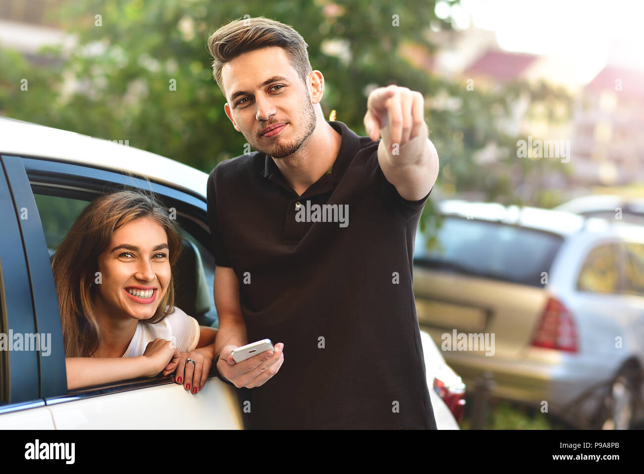 Beautiful girl sitting in the car and flirting with guy who outdoor standing Stock Photo