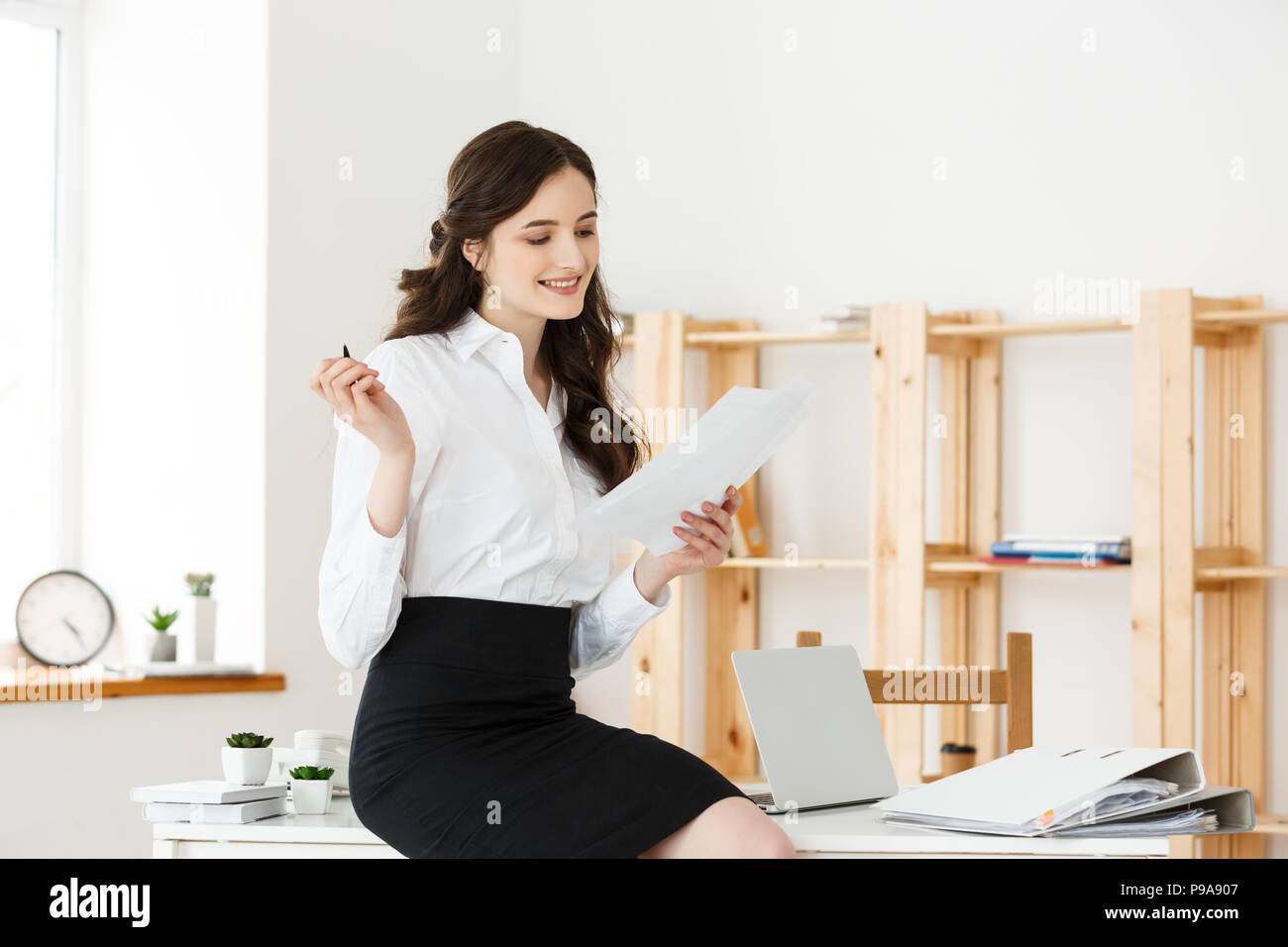 Happy young business woman or secretary holding document in modern ...