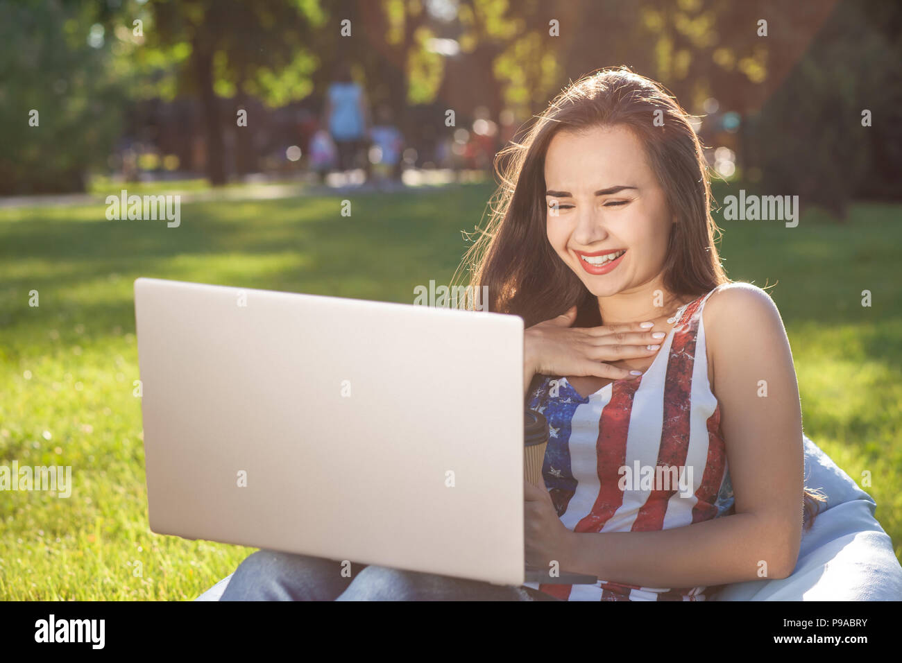 Pretty young woman sitting on bean bag use laptop while resting on ...