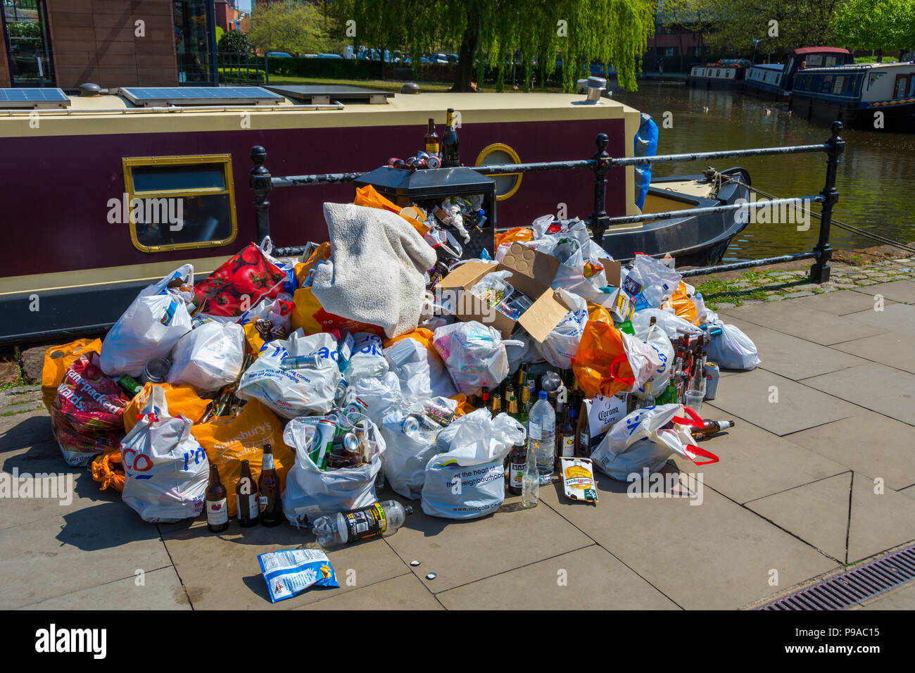Bags of rubbish around an overflowing waste bin after a hot and sunny bank holiday weekend, Castlefield Basin, Manchester, England, UK Stock Photo