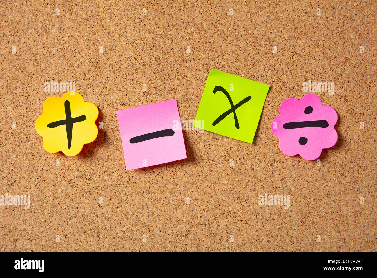School maths concept. Sticky colorful notes in flower shape isolated with math symbols on cork board background. Stock Photo