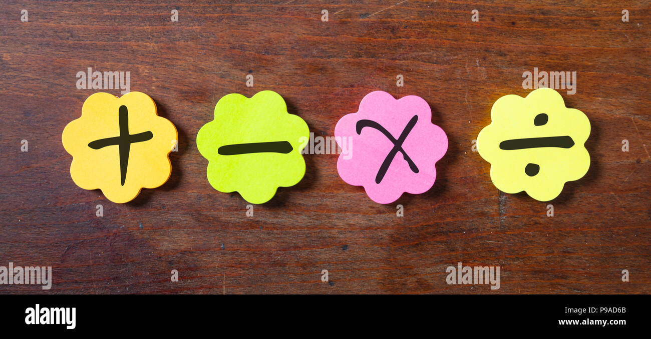 School maths concept. Sticky colorful notes in flower shape isolated with math symbols on wooden background. Stock Photo