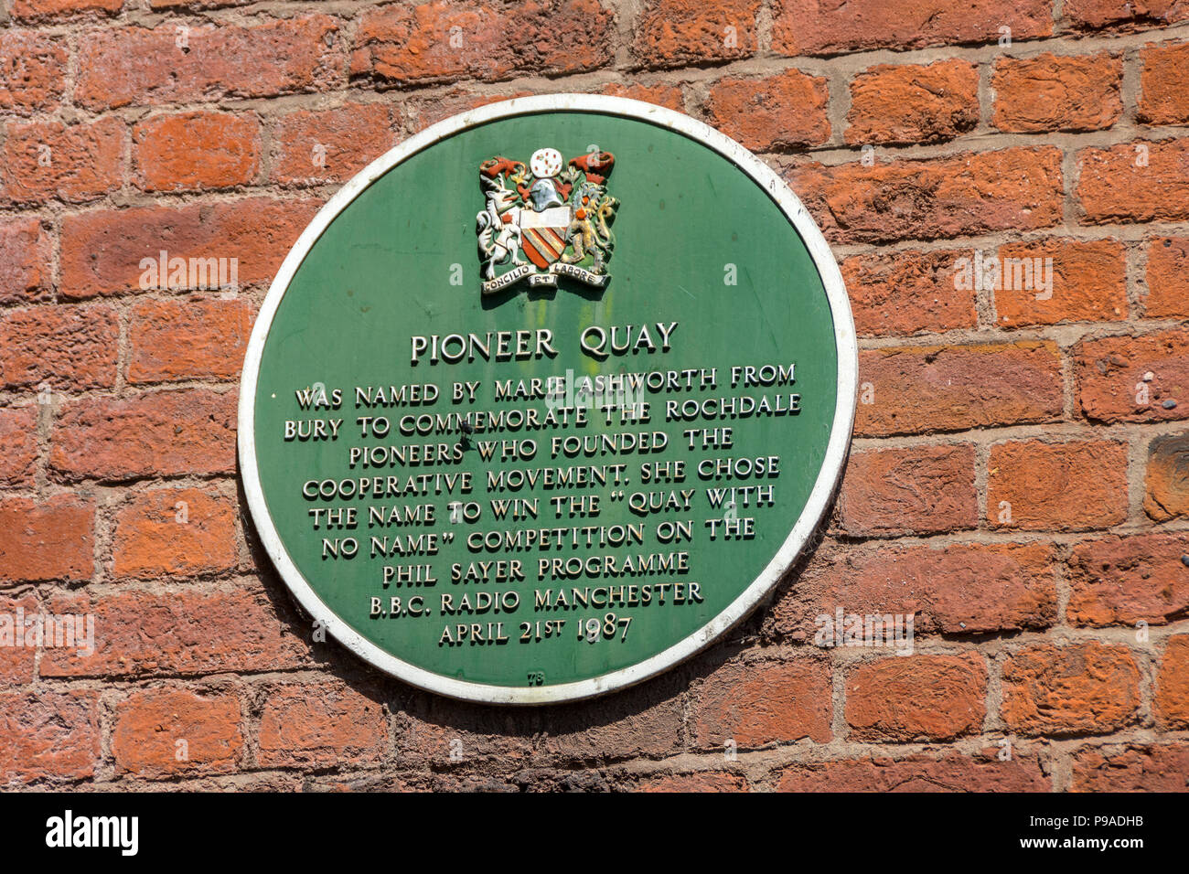 Green plaque at Pioneer Quay on the Rochdale Canal, Manchester, England, UK.  Commemorating the Rochdale Pioneers who founded the Cooperative movement Stock Photo