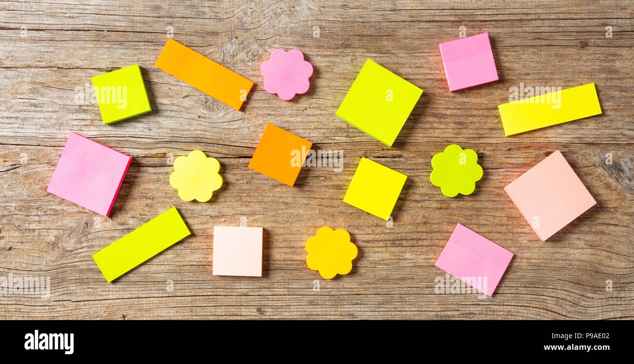 School concept. Sticky colorful notes in various shapes isolated with copy space on wooden background. Stock Photo