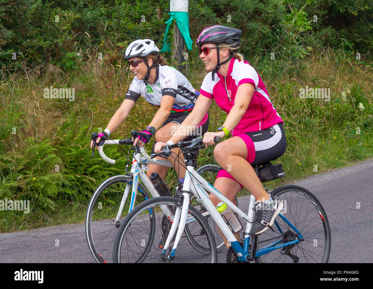 ladies riding bicycles down a country road in west cork, ireland Stock Photo