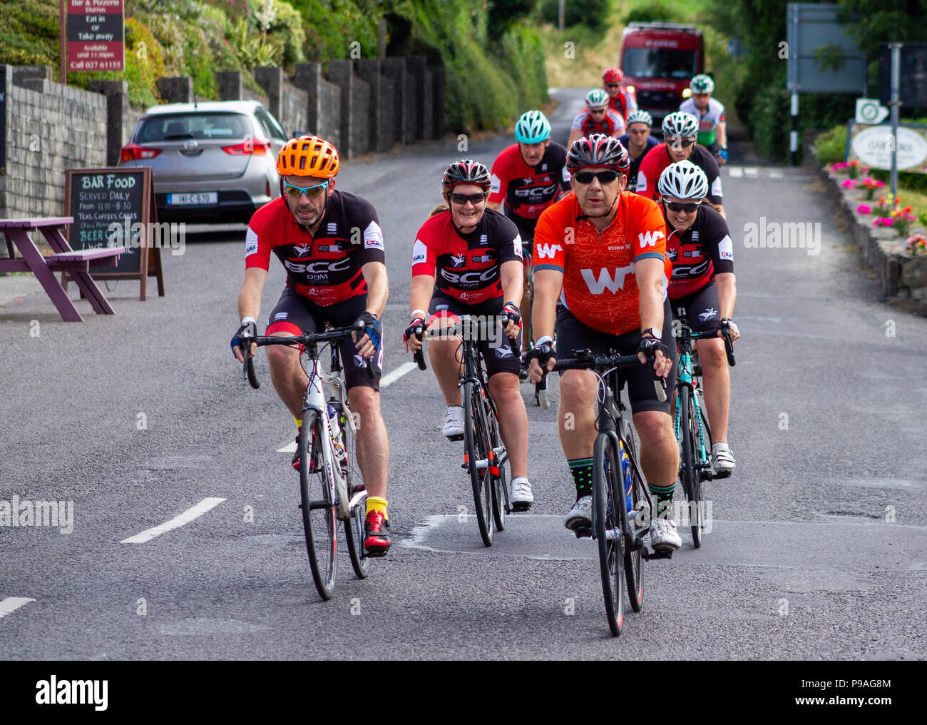 mixed group of cyclists riding through a village in west cork,  Ireland. Stock Photo