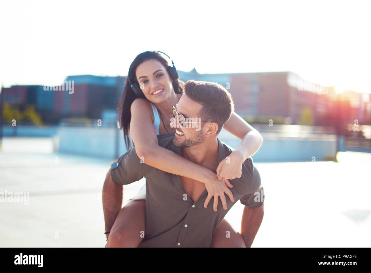 Happy young trendy urban couple have fun in city, riding piggyback Stock Photo