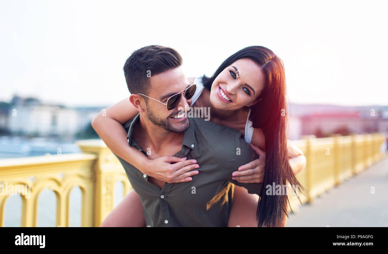 Happy brunette woman riding piggyback on boyfriend, fun Stock Photo