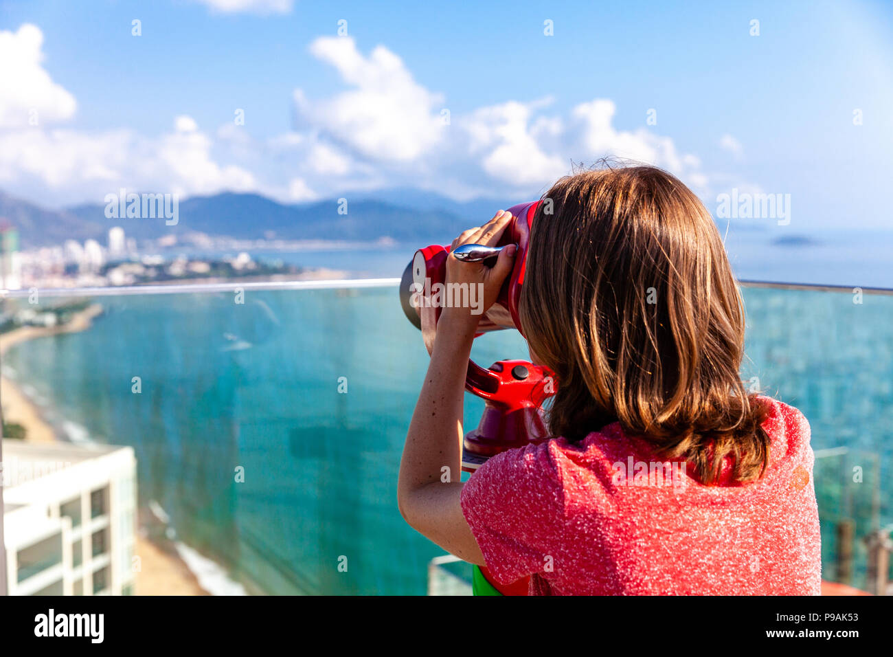 A young woman looks at the city through the tower viewer. Nha Trang, Vietnam. Stock Photo