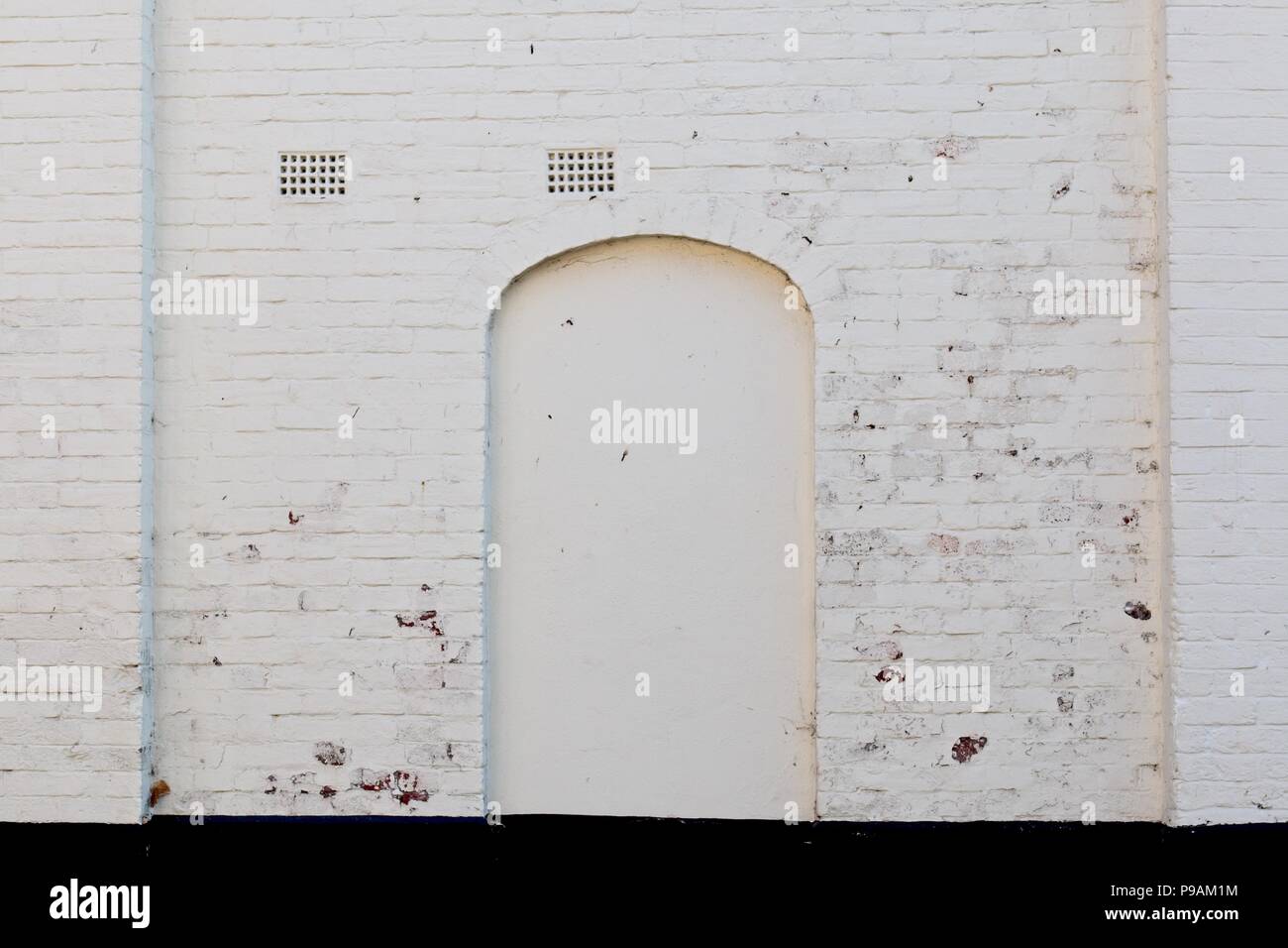 Old white whitewashed wall with briked up doorway door Stock Photo