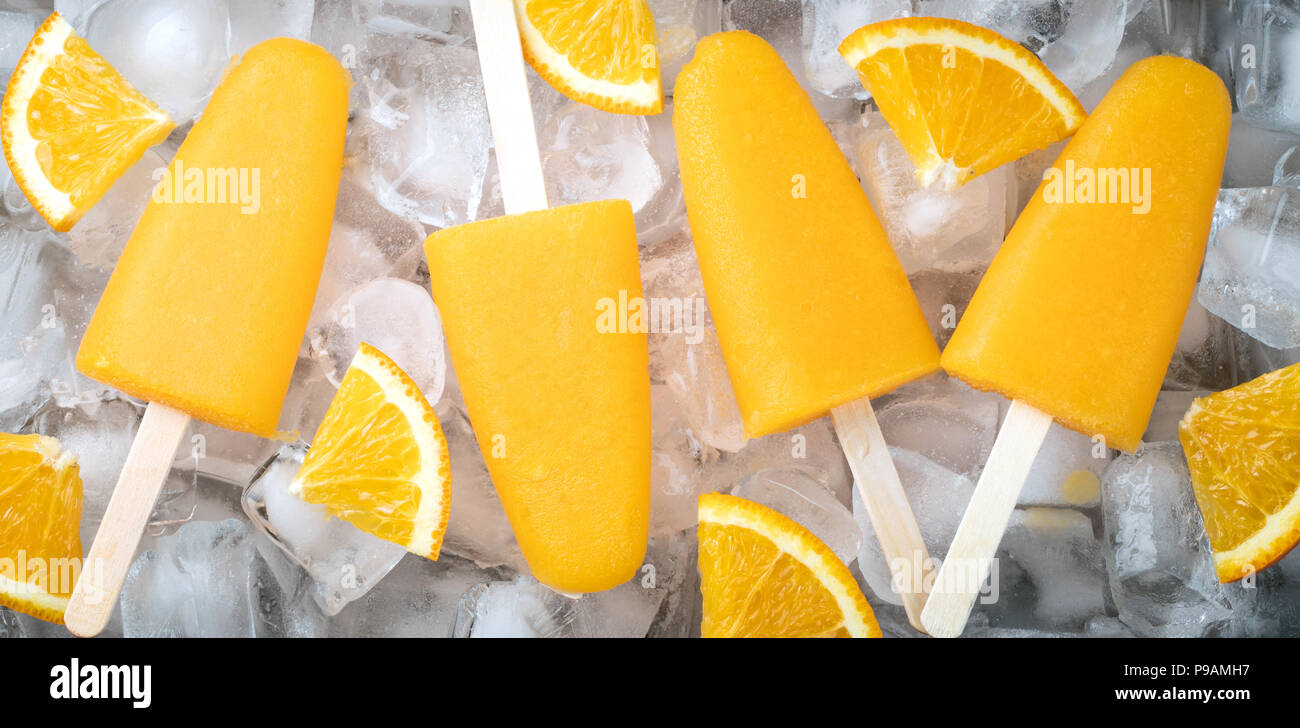 Orange popsicles with juice on a icecubes. Ice pops, flat lay, top view. Stock Photo