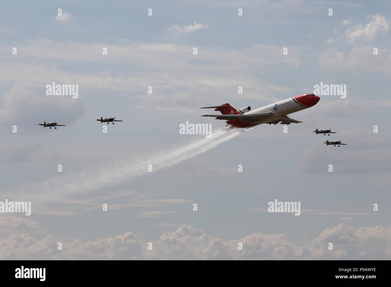 Farnborough, UK. 16th July 2018. Oil Spill Response organisation's Boeing 727 and The Blades aerobatic team perform a flypast on the opening day of the 2018 Farnborough International Airshow, one of the biggest aviation trade and industry events in the world, held in the UK. Credit: James Hancock/Alamy Live News Stock Photo