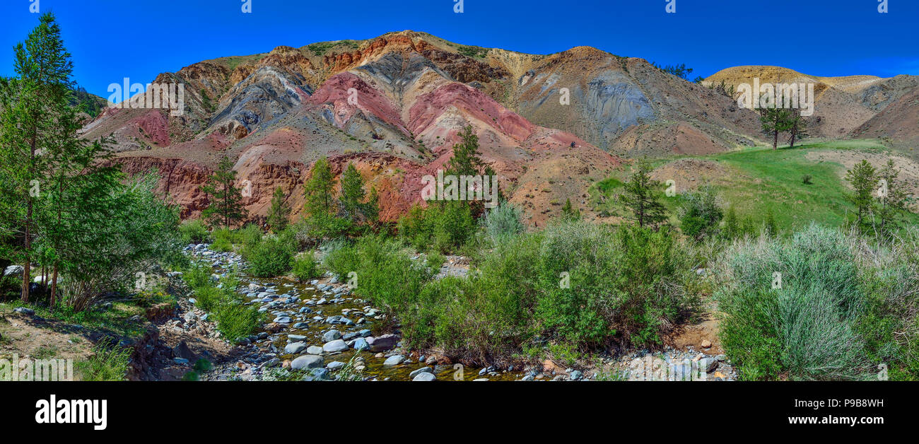 Panorama of unrealy beautiful colorful clay cliffs in Altai mountains, Russia. Summer landscape, which is called Martian and creek running between sto Stock Photo