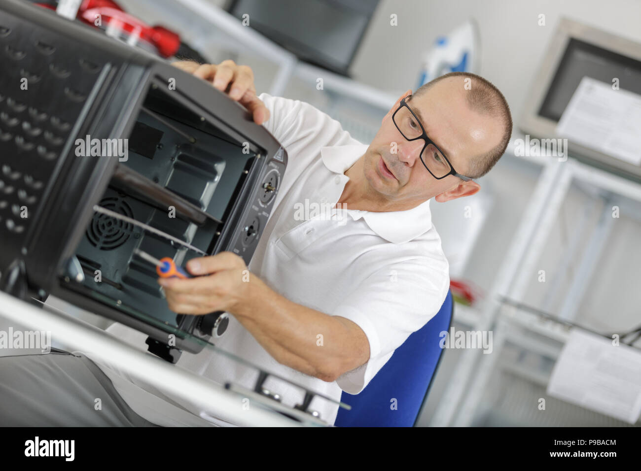 repairman working on a microwave in the kitchen Stock Photo