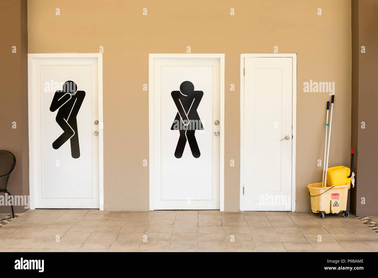 Comical black and white toilet door signs and cleaning bucket in Orangestad, Aruba, Caribbean Stock Photo