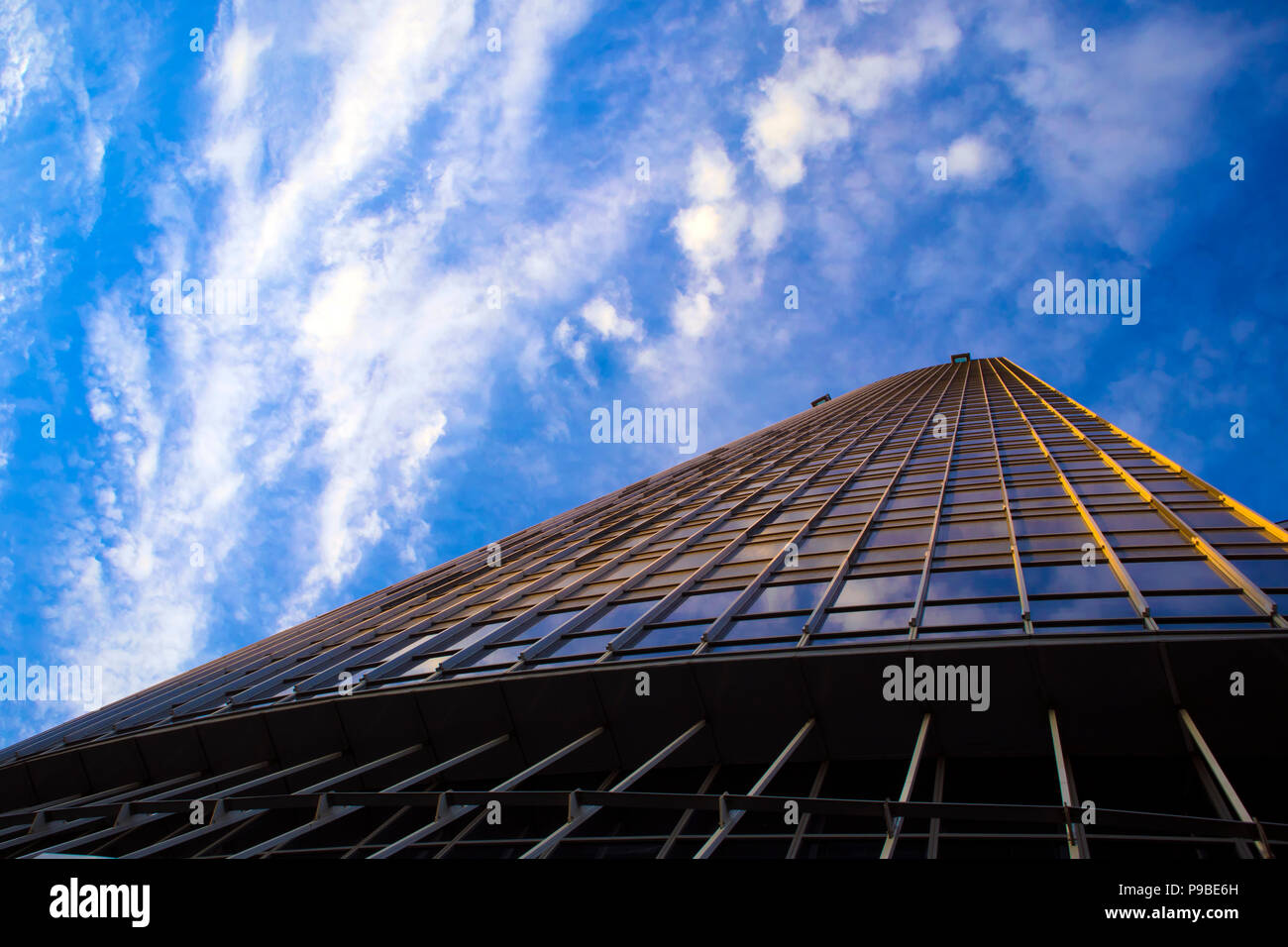 Bottom view of modern skyscraper outgoing to the blue sky with white clouds Stock Photo