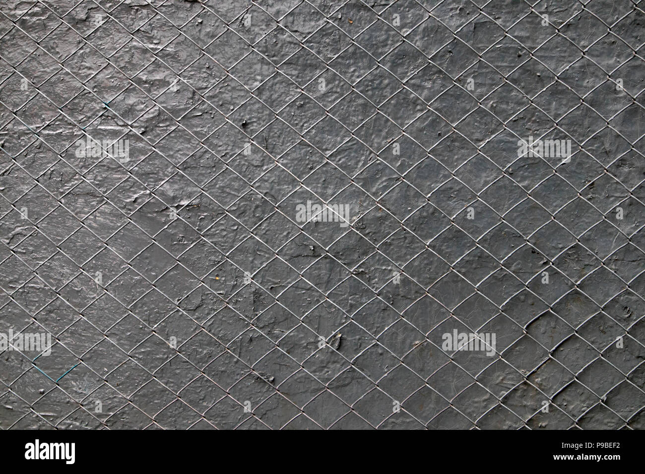 Gray painted steel mesh stretched over painted plaster surface, may be used as background or texture Stock Photo