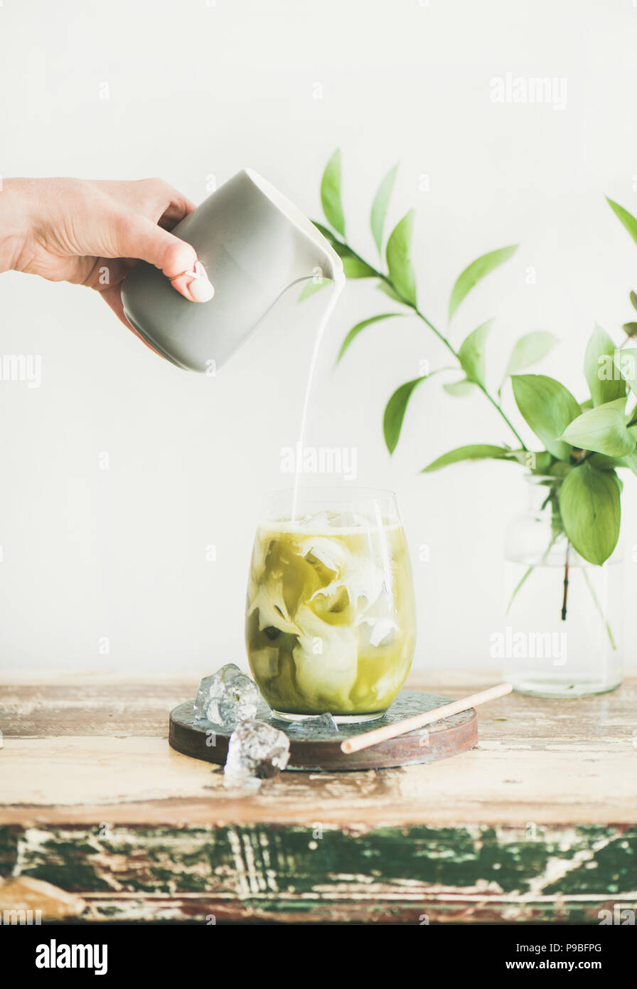 Iced matcha latte drink with coconut milk pouring from pitcher Stock