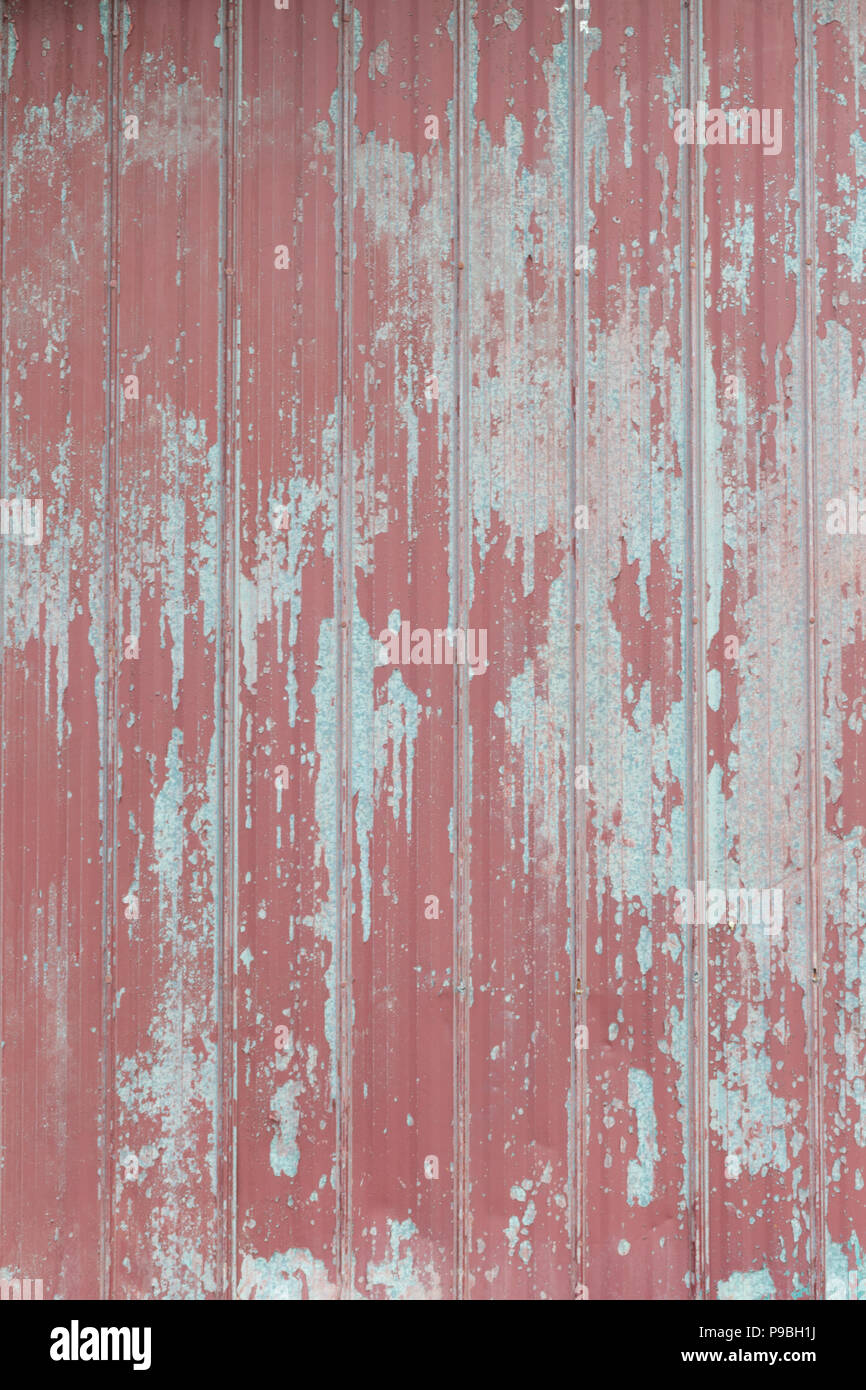 Faded peeling rusty steel sheets with oxblood red paint. Grunge