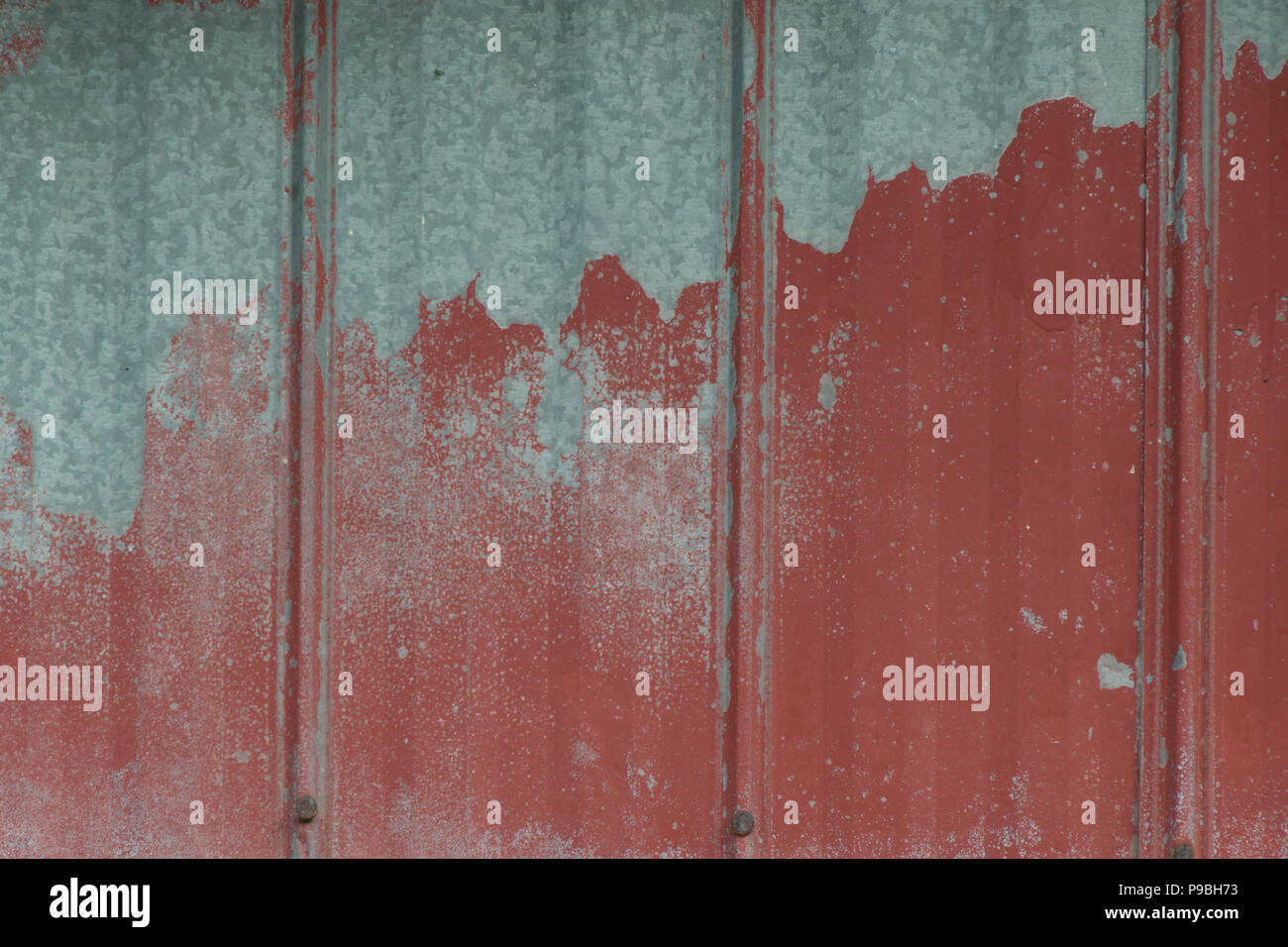 Faded peeling rusty steel sheets with oxblood red paint. Grunge