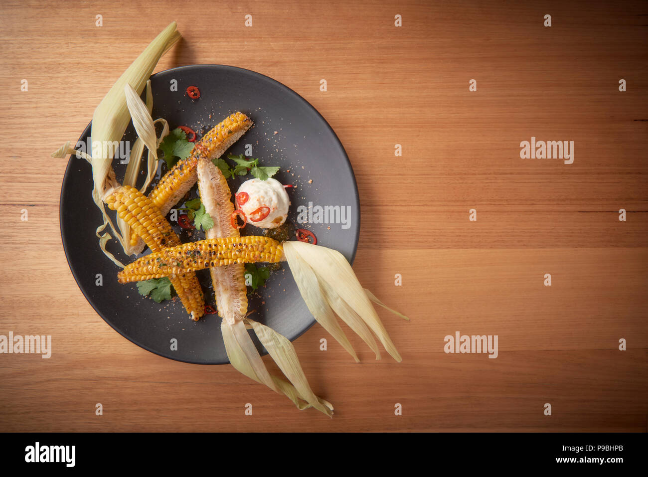 Quartered chargrilled corn on the cob with chilli and sour cream Stock