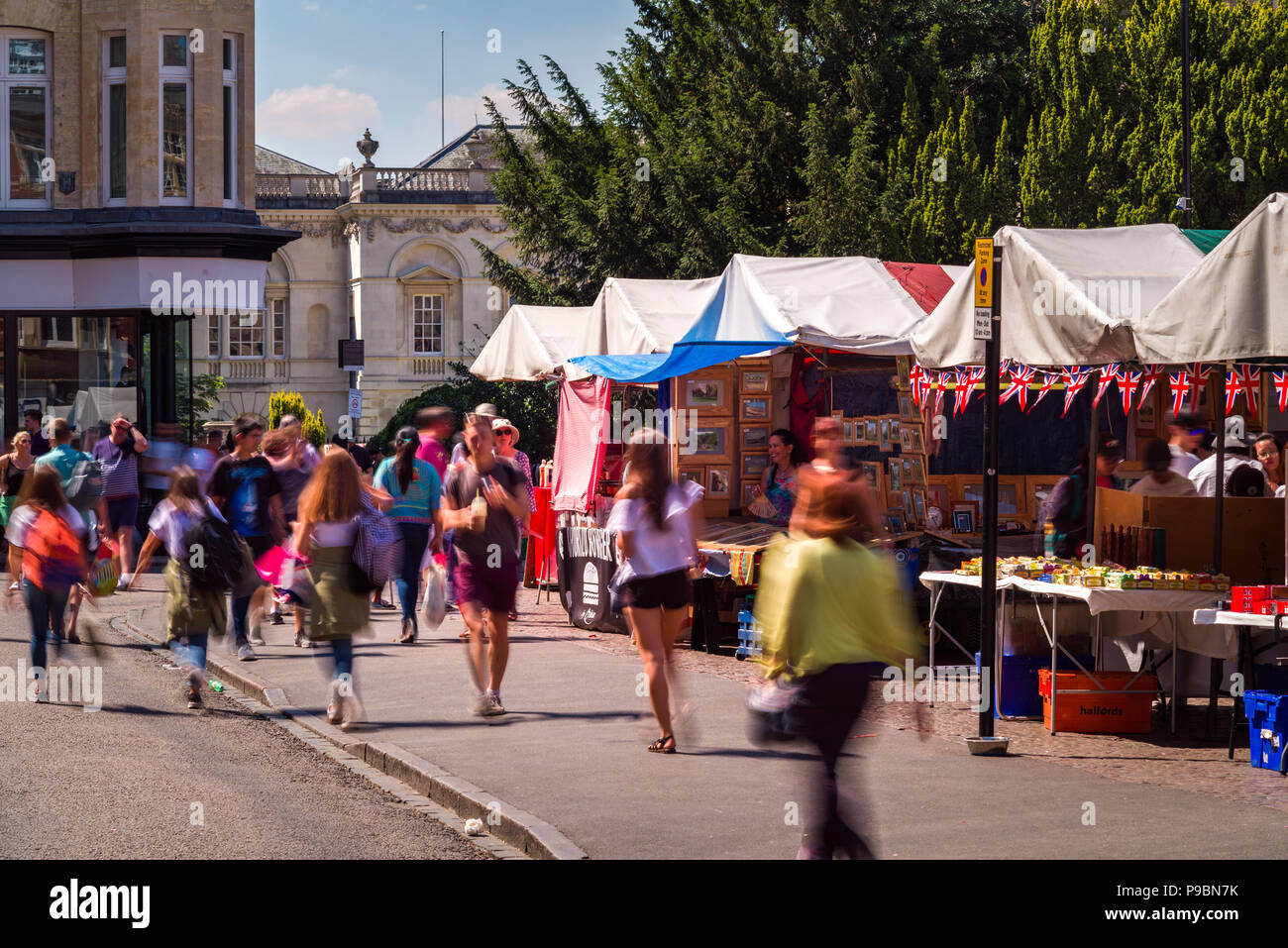 People browsing and walking past outdoor market stalls in Market street, Cambridge, UK Stock Photo