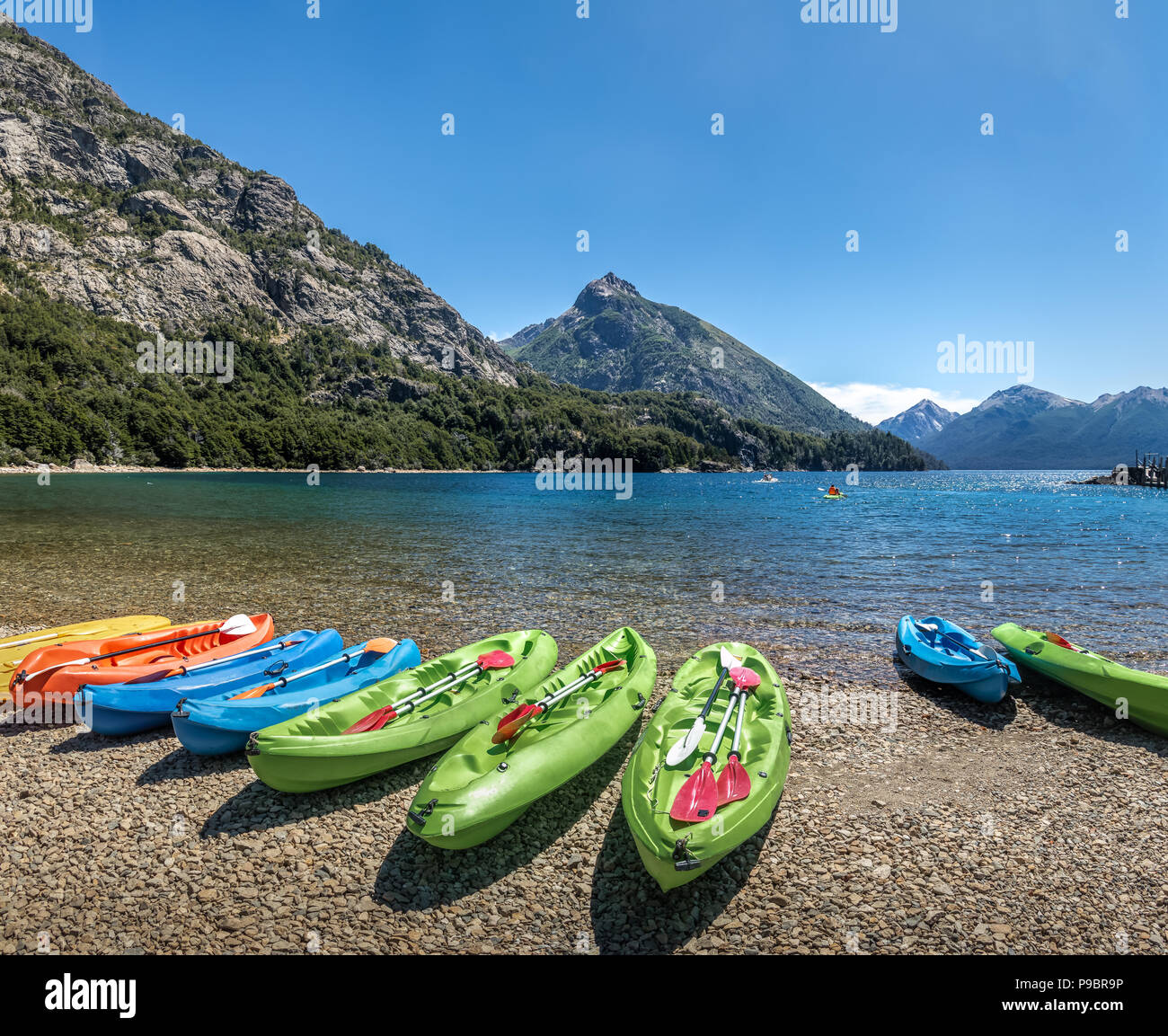 Colorful Kayaks in a lake surrounded by mountains at Bahia Lopez in Circuito Chico  - Bariloche, Patagonia, Argentina Stock Photo