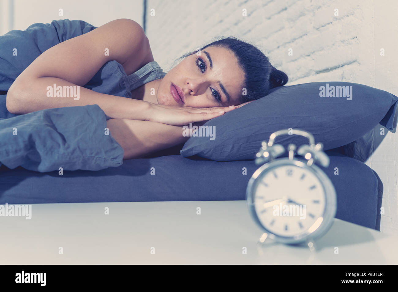 young beautiful hispanic woman at home bedroom lying in bed late at night trying to sleep suffering insomnia sleeping disorder or scared on nightmares Stock Photo