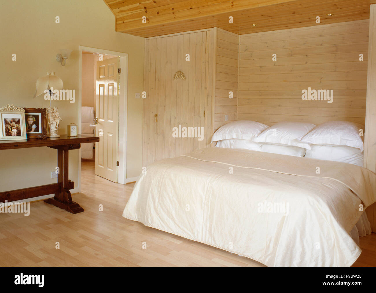 Light Wood Panelled Wall Behind Bed With White Pillows And Cream