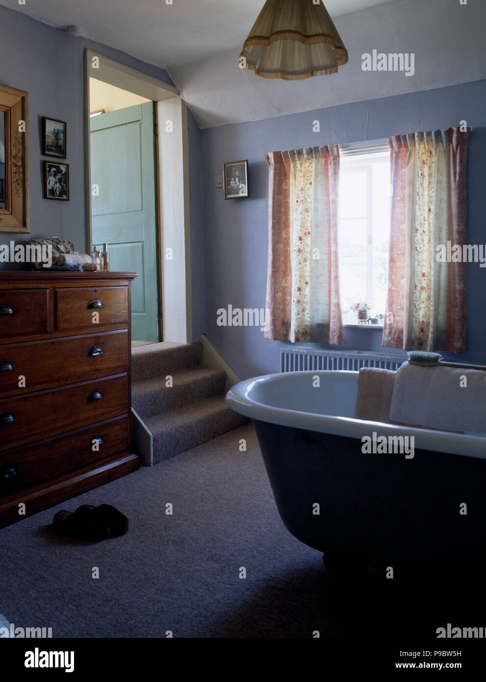 Roll top bath in a pale blue bathroom with an antique chest of drawers ...