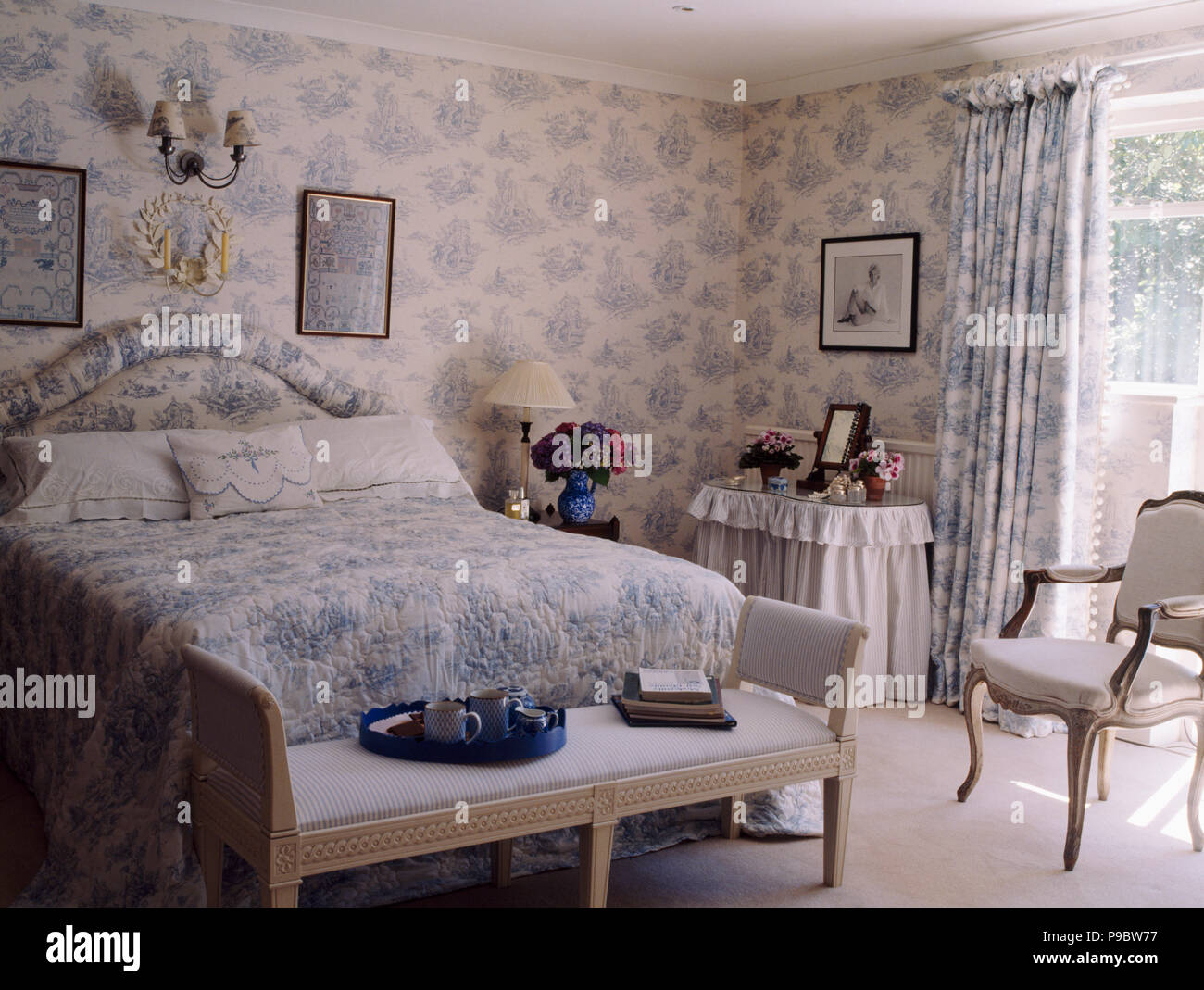 Blue+white Toile-de-Jouy wallpaper and curtains and bedlinen in country bedroom Stock Photo