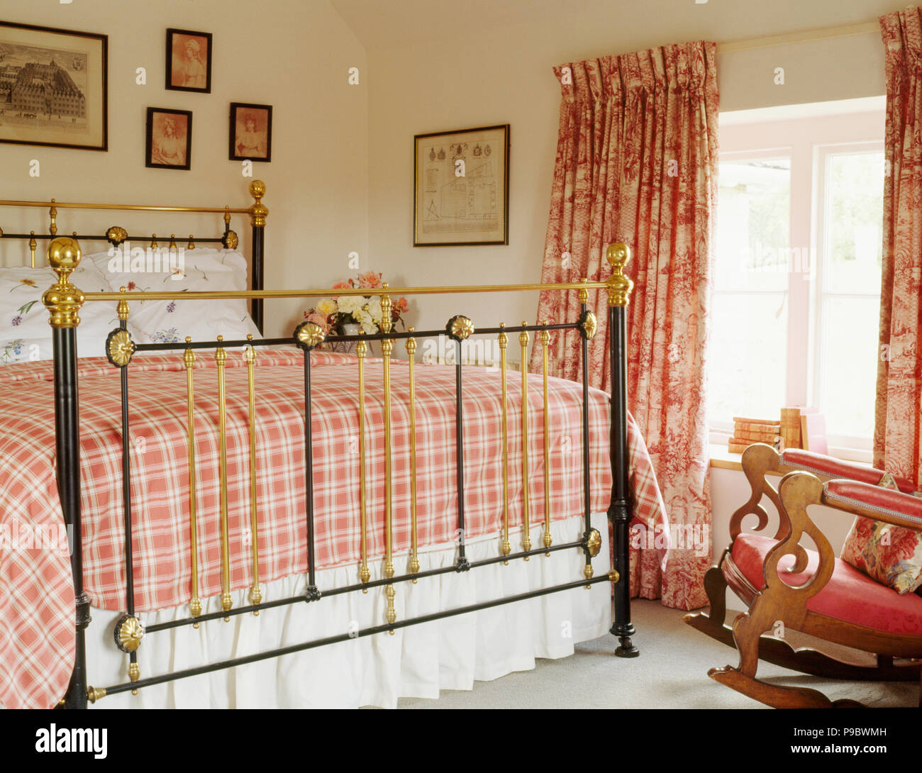 Red checked bedlinen on antique brass bed in country bedroom Stock Photo