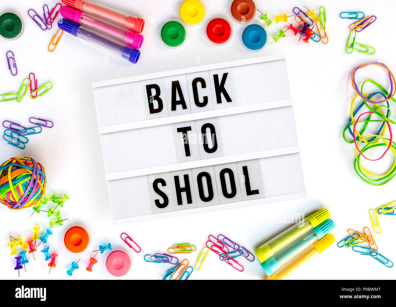 Back to school written in a light box, colorful school supplies isolated on white Stock Photo