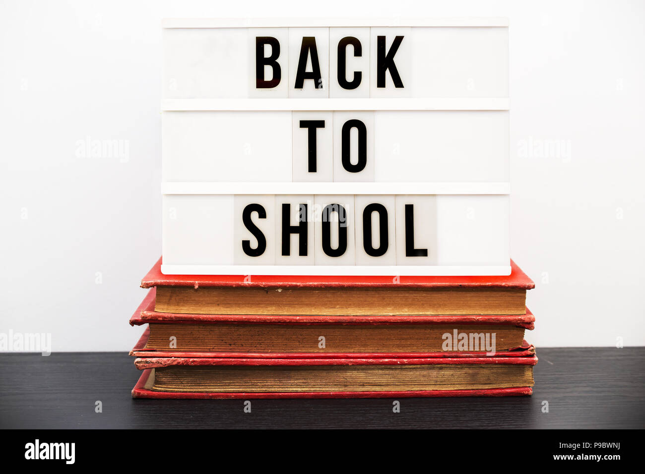 Back to school written in a light box on top of a pile of old  books Stock Photo