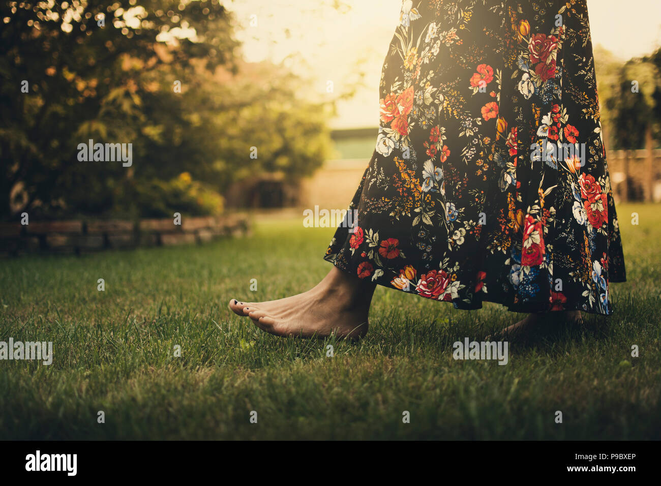 woman walking barefoot on the grass in sunlight Stock Photo