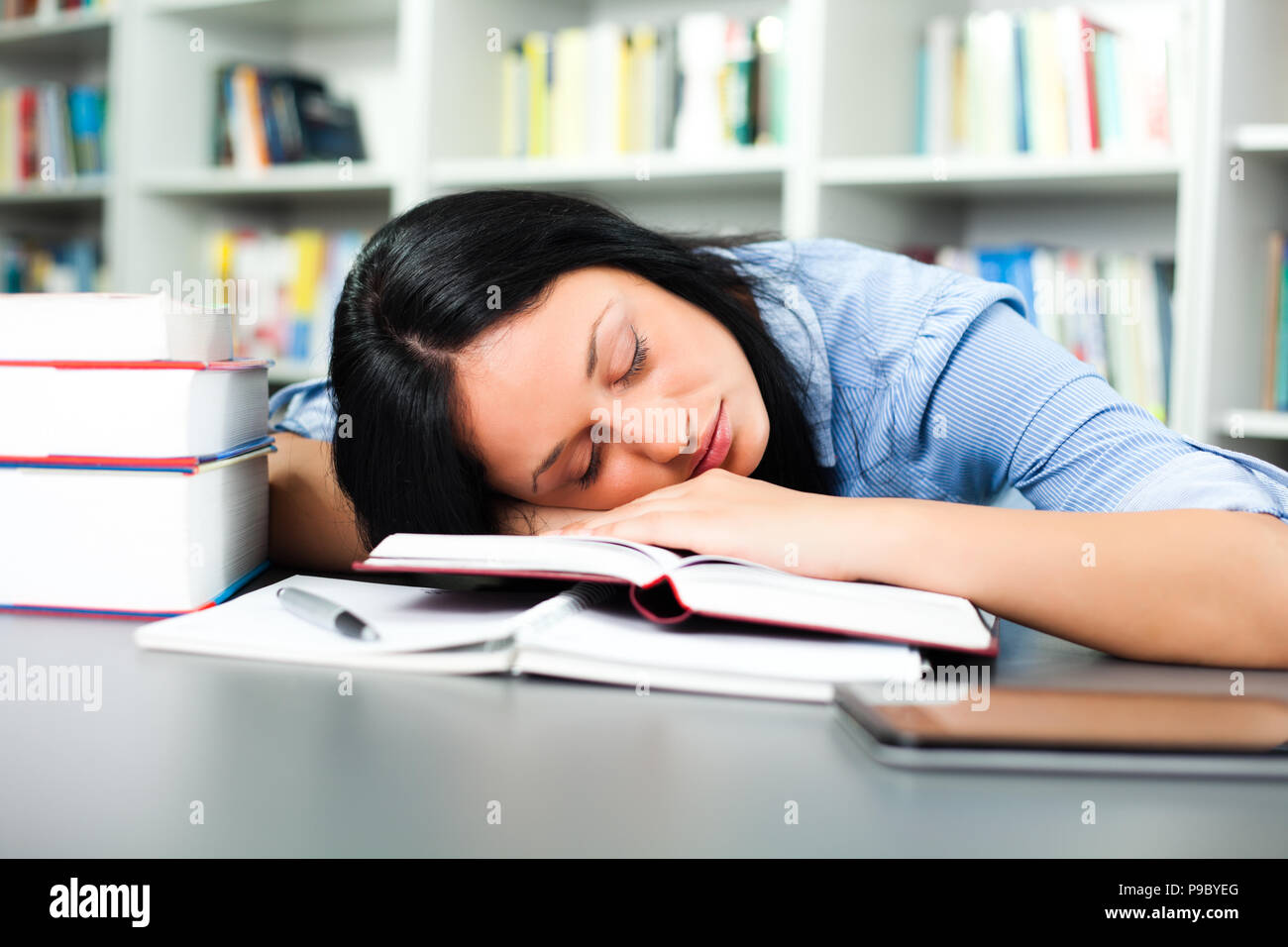 Tired student sleeping in library Stock Photo