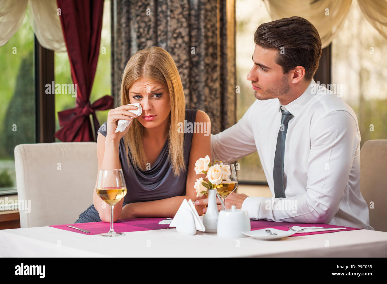 Young man is consoling his girlfriend at the restaurant Stock Photo