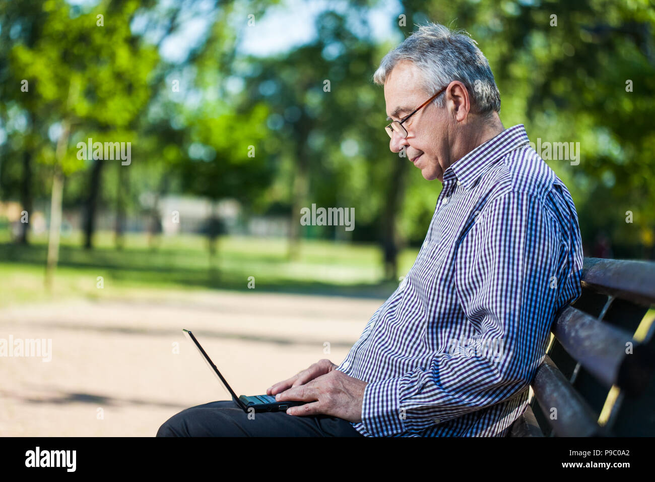 Senior man using laptop in park Stock Photo