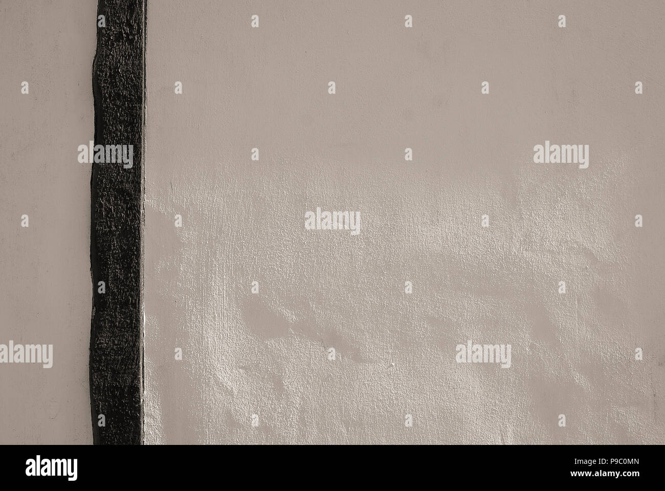 An off-white wall with black timber feature showing texture of plasterwork. Suitable for use as a background Stock Photo