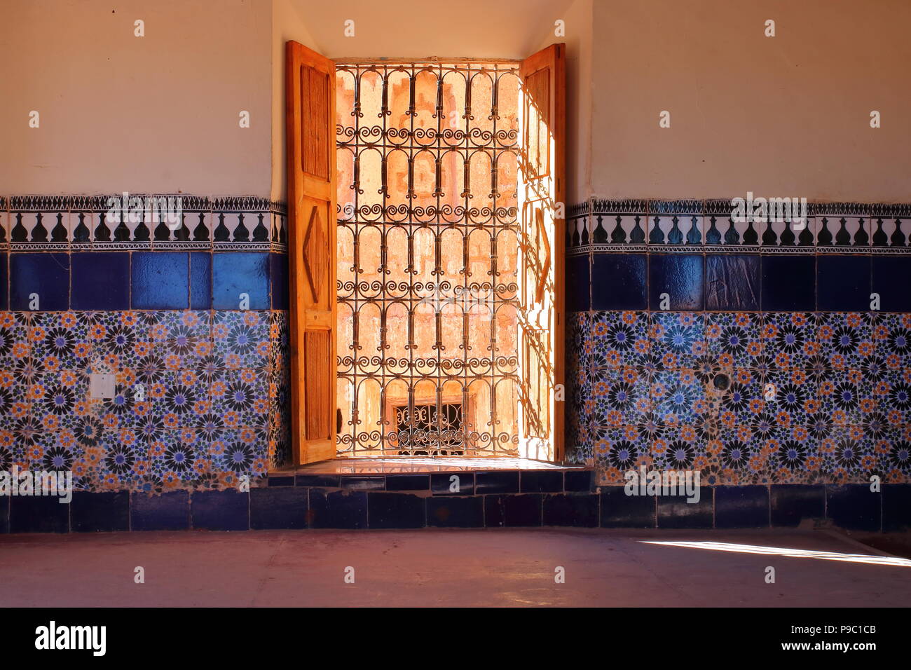 Decorative wall covered with decorative traditional pattern tiles into moroccan palace called kasbah, open window with wooden made shutters, sunny Stock Photo