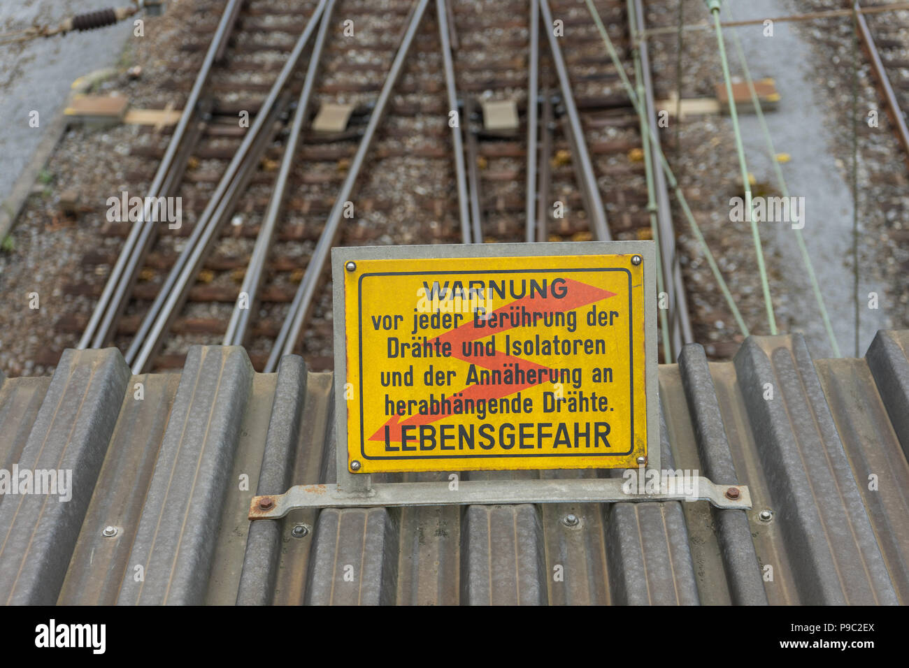 attention high voltage sign near train tracks in german language Stock