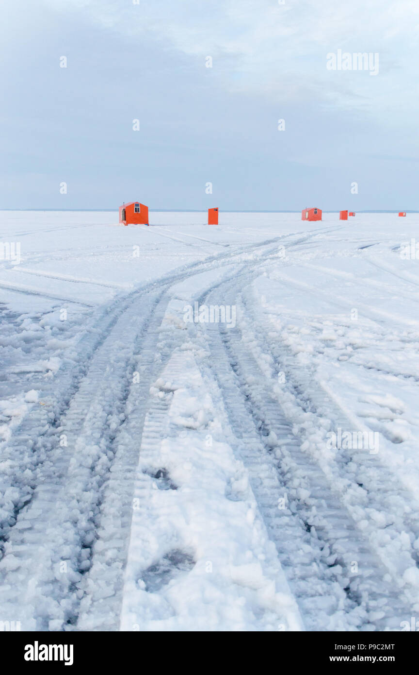 Orange Ice fishing huts on a frozen lake in Ontario at sunset showing