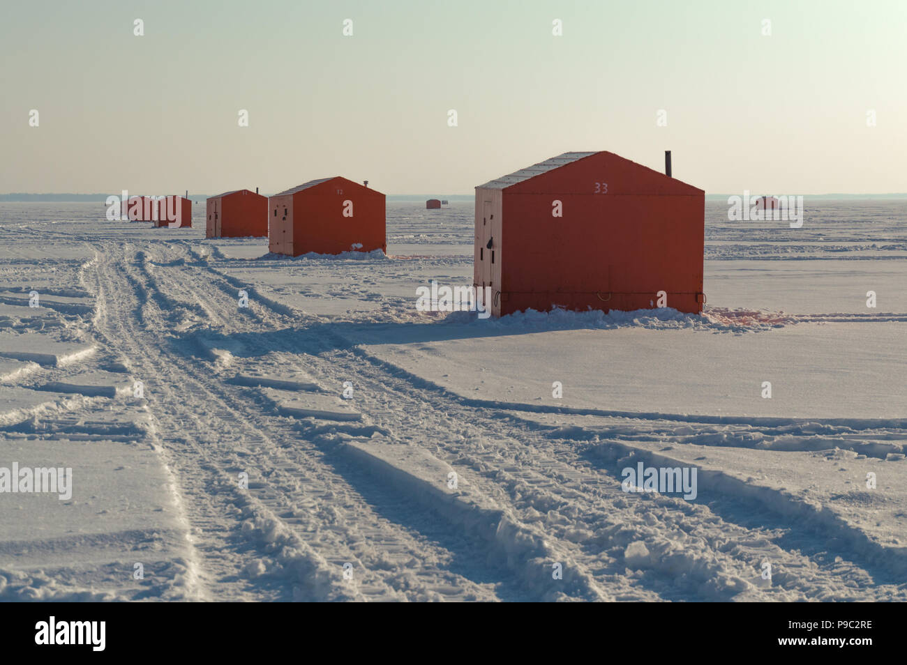 Orange Ice fishing huts on a frozen lake in Ontario at sunset showing