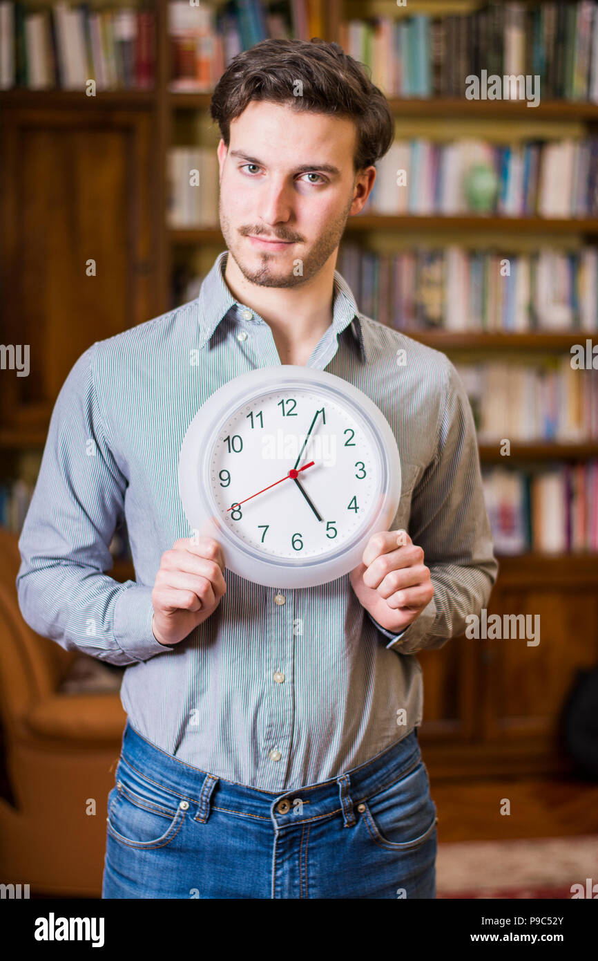 Young man scared of time holding clock Stock Photo Alamy