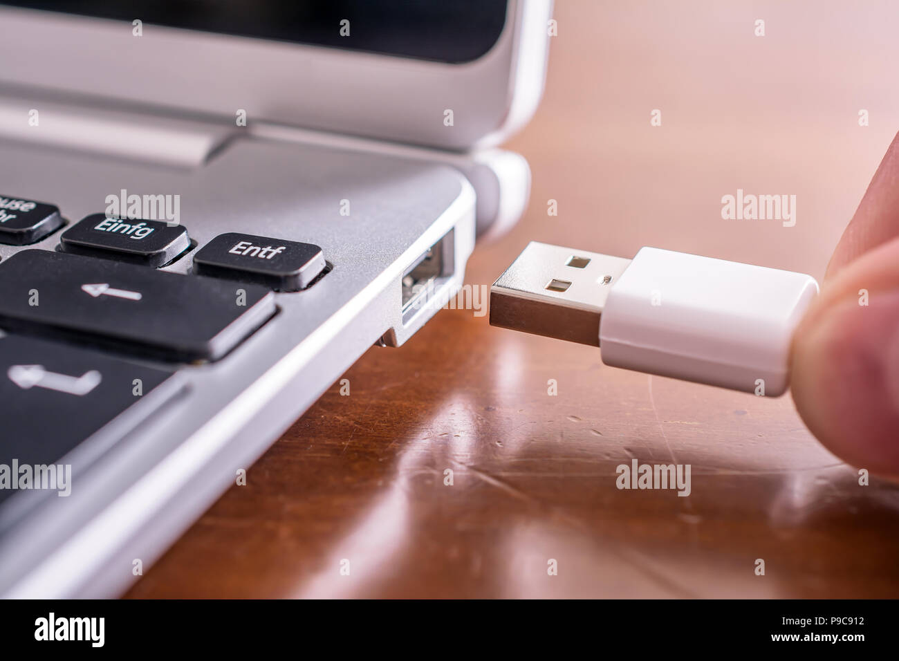 Male Hand Connecting A White USB Cable To The USB Port Of A Small