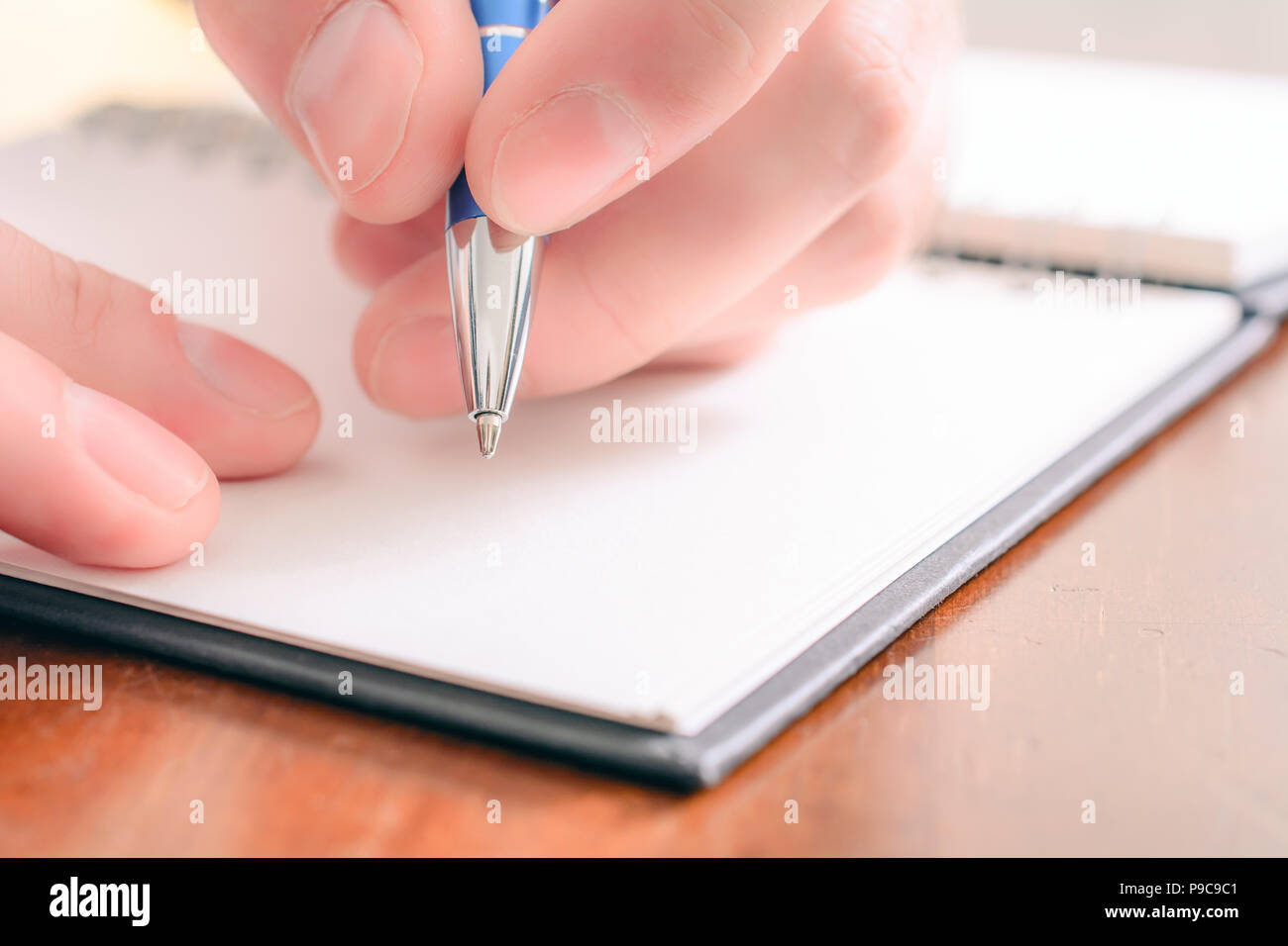 Macro Of A Male Hand Writing In A Blank Organizer With A Biro Stock Photo