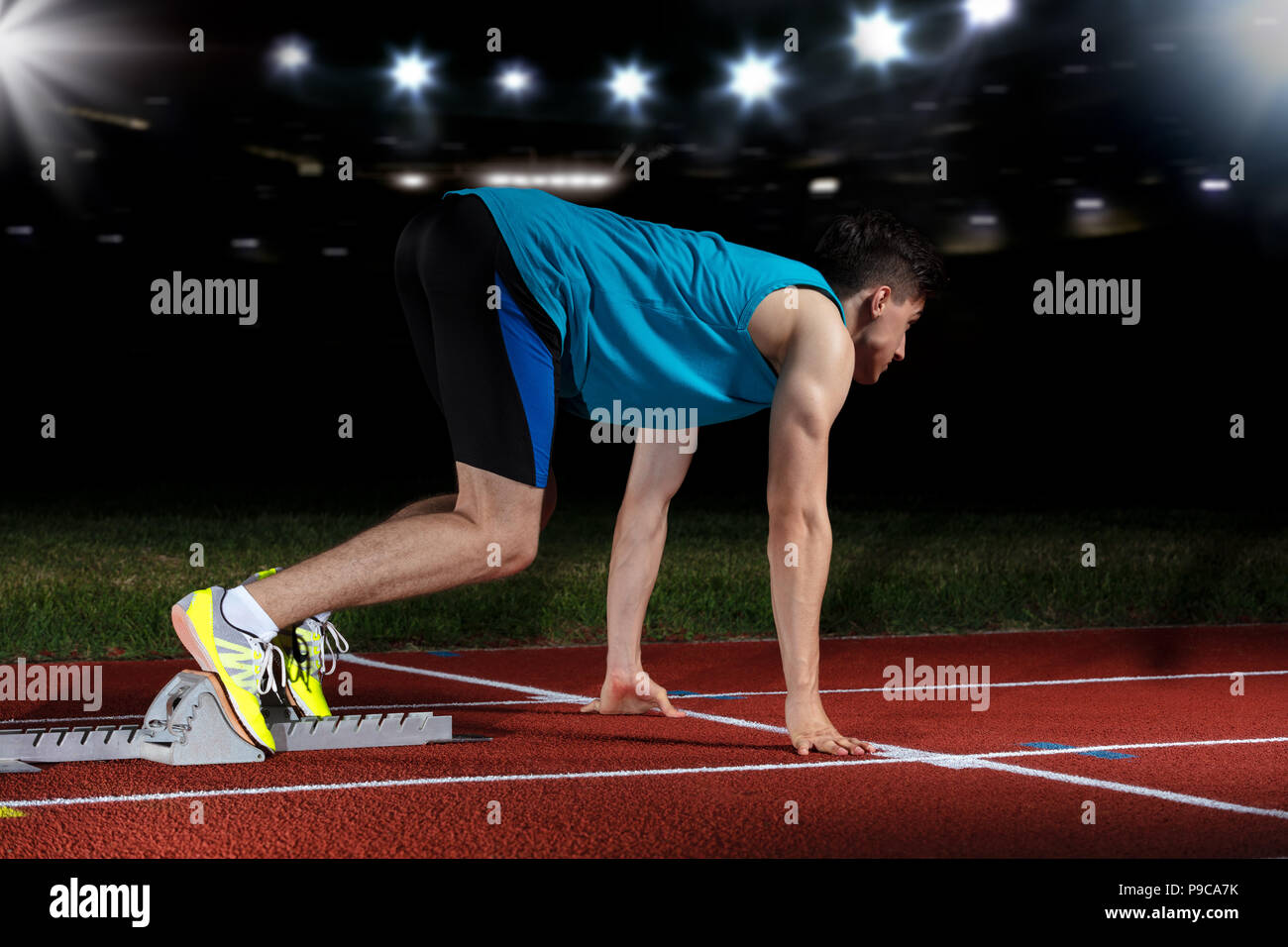 Sprinter leaving starting blocks on the running track in front of big