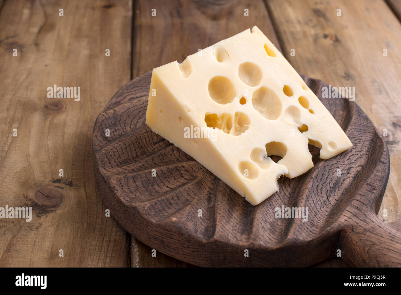 Dutch cheese with holes on a wooden old board. Vintage photo. Dairy. Free space for text. Copy space Stock Photo