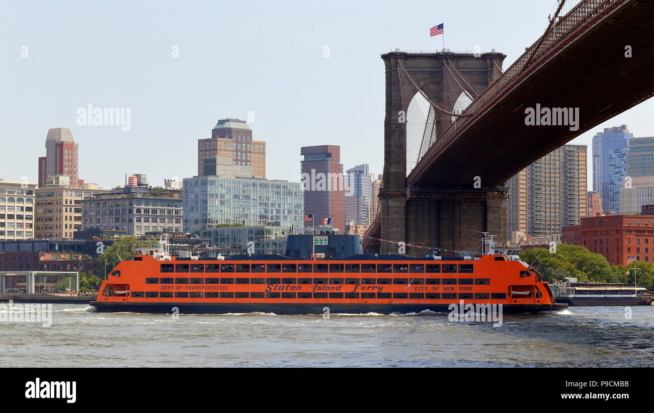 A Staten Island Ferry boat passes under the Brooklyn Bridge Stock Photo