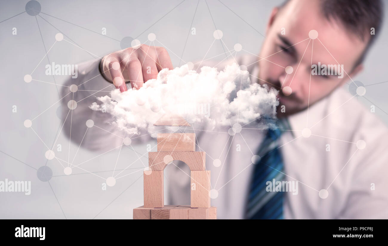 Young handsome businessman using wooden building blocks behind cloud ...